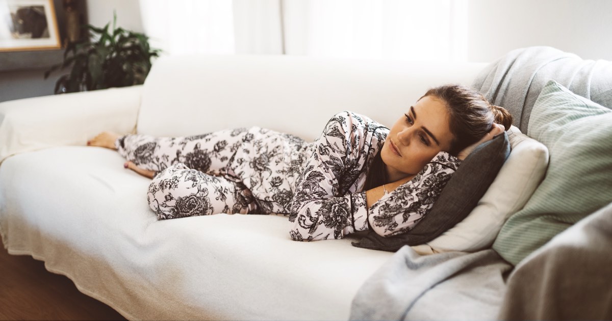 Schwangere Frau liegt traurig auf Couch