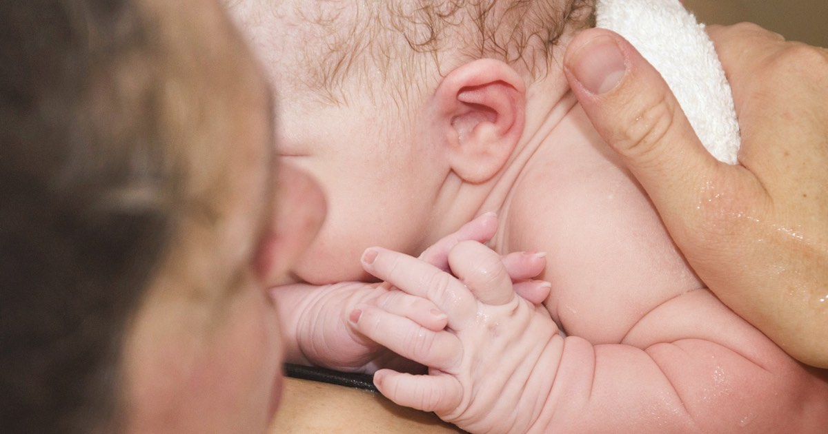 Junge Mutter hält Baby auf der Brust