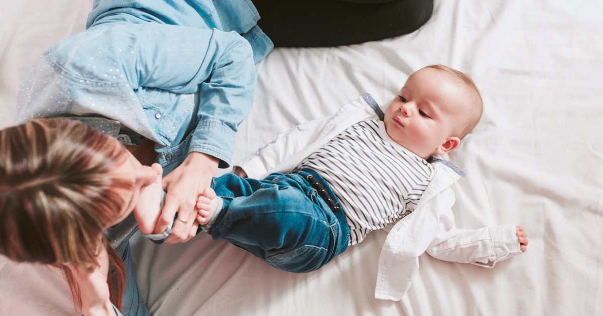Junge Mutter liegt mit Baby im Bett