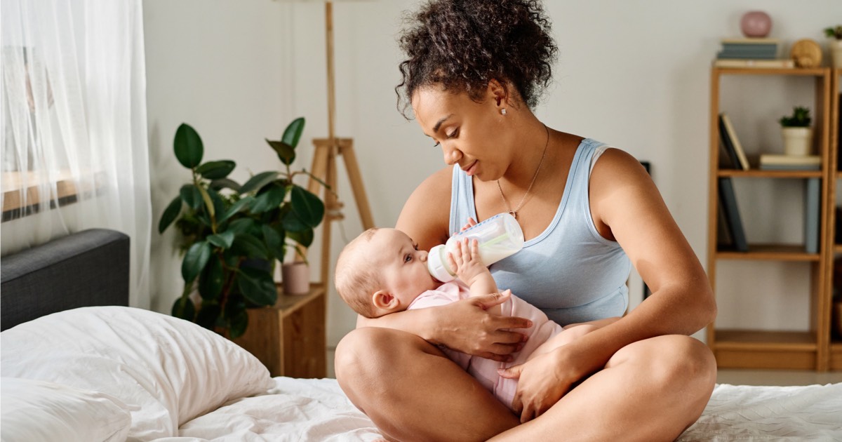 Junge Mutter und ihr Baby mit voller Milchflasche